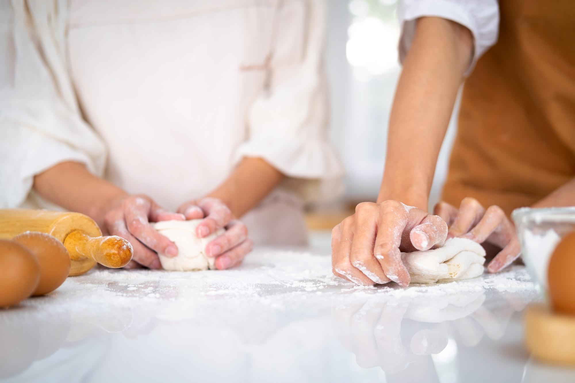 Close-up of hands folding dough in a bright kitchen